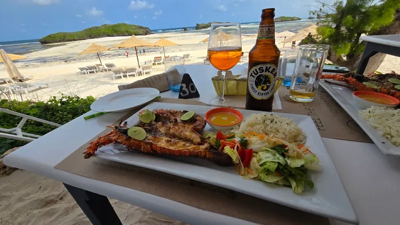 Grilled lobster with rice and salad, served on the beach