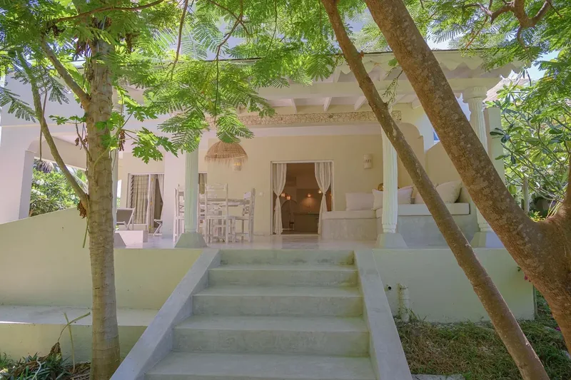 Villa Maji's entrance steps up to a shaded veranda under the trees