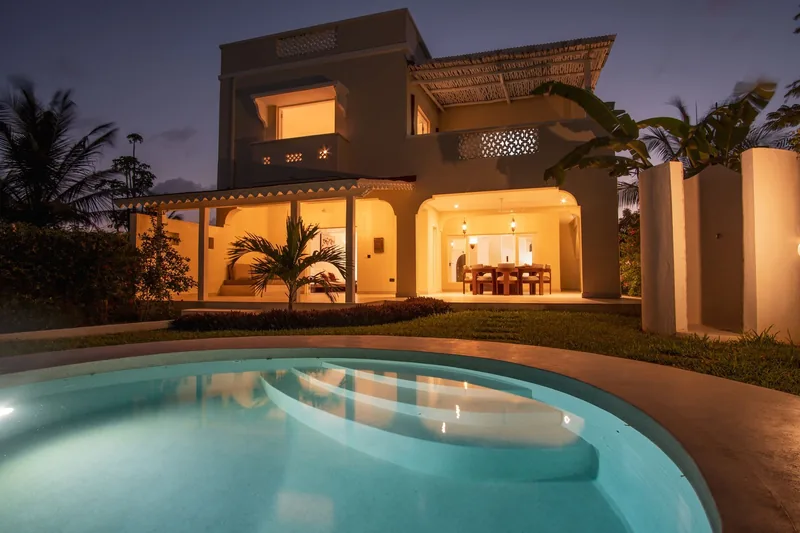 The Usalu Villa at dusk, lit interior and pool in front
